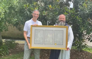 Louisiana Senator Fred Mills standing with Fr. Michael Champagne holding a framed copy of Senate Resolution No. 116. Credit: Jennifer Angelle. 