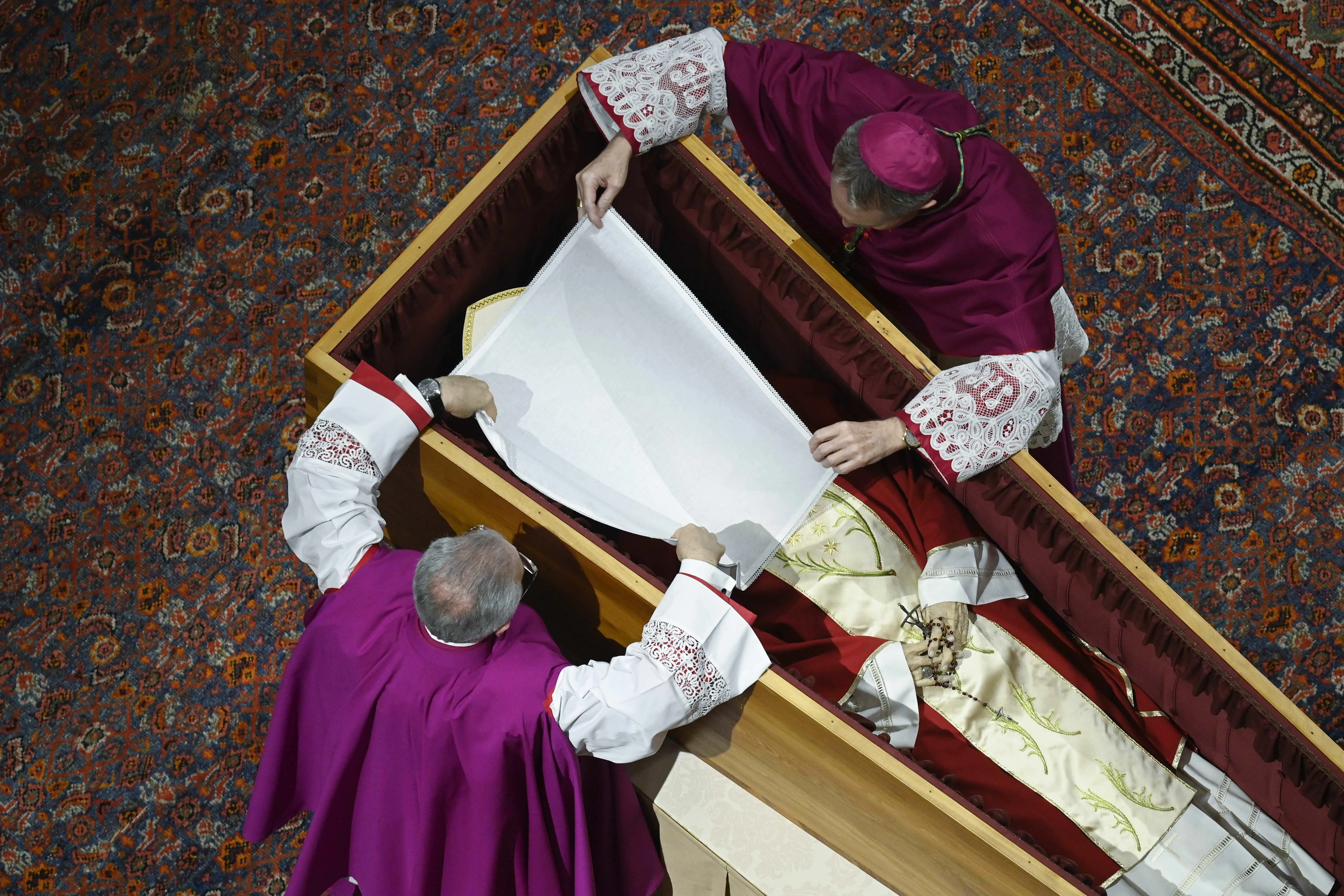 Before the wooden coffin is closed, Benedict XVI’s personal secretary Archbishop Georg Gänswein and Monsignor Diego Giovanni Ravelli, the Vatican’s lead master of ceremonies for papal liturgies, place a white veil over the late pope’s face. The action on Jan. 4, 2023, is part of the funeral rites for popes.?w=200&h=150