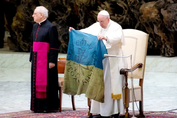 Pope Francis holds up a flag which he said was brought to him from “the martyred city” of Bucha, Ukraine at his general audience on April 6, 2022.