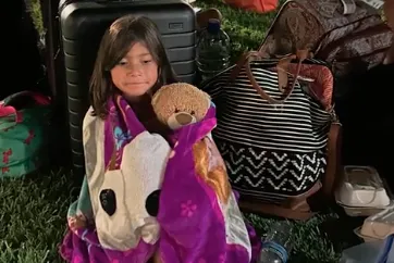 One of the Cardenas children huddles with the family's luggage as the family attempts to flee Maui. Angel Cardenas/screengrab