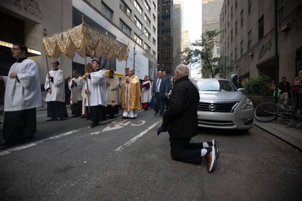 A bystander kneels as the Blessed Sacrament passes by during a Eucharistic procession on the streets of New York City on Oct. 10, 2023. Credit: Jeffrey Bruno