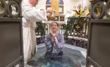 A young woman is baptized at the 2024 Easter Vigil at St. Mary’s Catholic Center at Texas A&M.