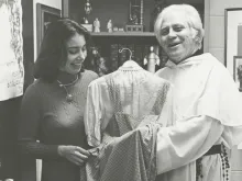 Fr. Gilbert Hartke holds a dress gifted to him that Judy Garland wore as Dorothy Gale in the 1939 film ‘The Wizard of Oz’.