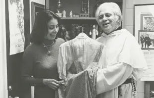 Fr. Gilbert Hartke holds a dress gifted to him that Judy Garland wore as Dorothy Gale in the 1939 film ‘The Wizard of Oz’. Courtesy of The Catholic University of America.