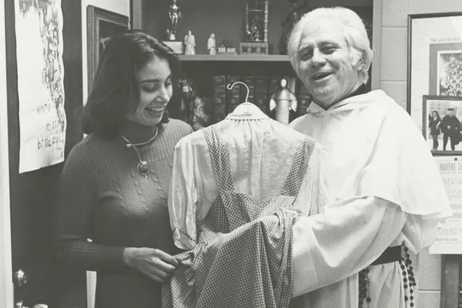 Fr. Gilbert Hatke holds a dress gifted to him that Judy Garland wore as Dorothy Gale in the 1939 film ‘The Wizard of Oz’.