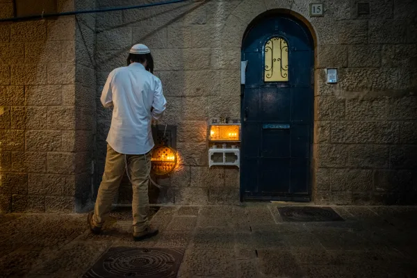 A religious Jew prays in front of Hanukkah candles during the lighting of Hanukkah candles on Dec. 9, 2023, in the Jewish quarter of Jerusalem's Old City. Credit: Marinella Bandini