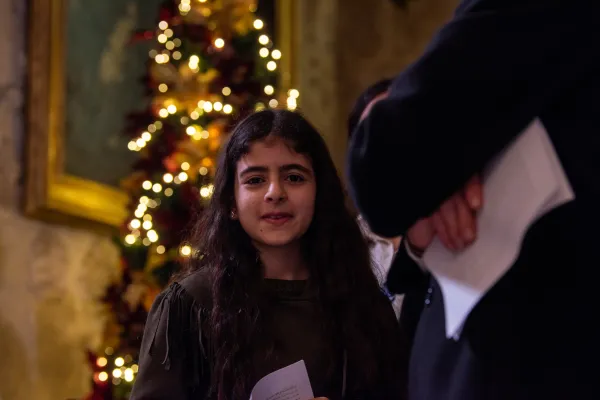 A young girl participates in the Midnight Mass of Christmas in Bethlehem. Behind her, a Christmas tree stands tall. The church was filled with local faithful, who this year took the place of pilgrims. Dec. 25, 2023. Credit: Marinella Bandini