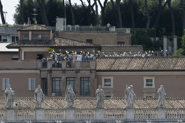 People wave from a nearby rooftop as Pope Francis delivers his Angelus address on June 18, 2023. Vatican Media