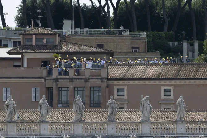 People wave from a nearby rooftop as Pope Francis delivers his Angelus address  on June 18, 2023.