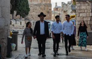 A family of religious Jews walks at the beginning of Armenian Quarter Street, the entry point to the Armenian Quarter of Jerusalem in April 2024. Behind them stands the complex of the Tower of David Museum. Credit: Marinella Bandini