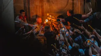 The "Holy Fire" is passed from inside Christ's tomb to pilgrims gathered inside the Basilica of the Holy Sepulcher in Jersusalem on May 4, 2024, for the annual Orthodox Christian ceremony, held on the day before Easter, according to the Julian calendar.