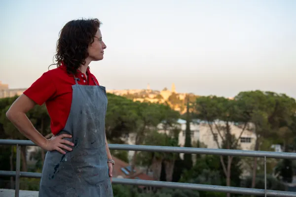 Iconographer María Ruiz Rodríguez on her terrace looking at the horizon. In the background are the walls of Jerusalem and the outline of the Basilica of the Dormition, November 2023. Credit: Marinella Bandini