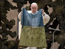 Pope Francis holds a flag that he received from Bucha, Ukraine at his general audience on April 6, 2022.