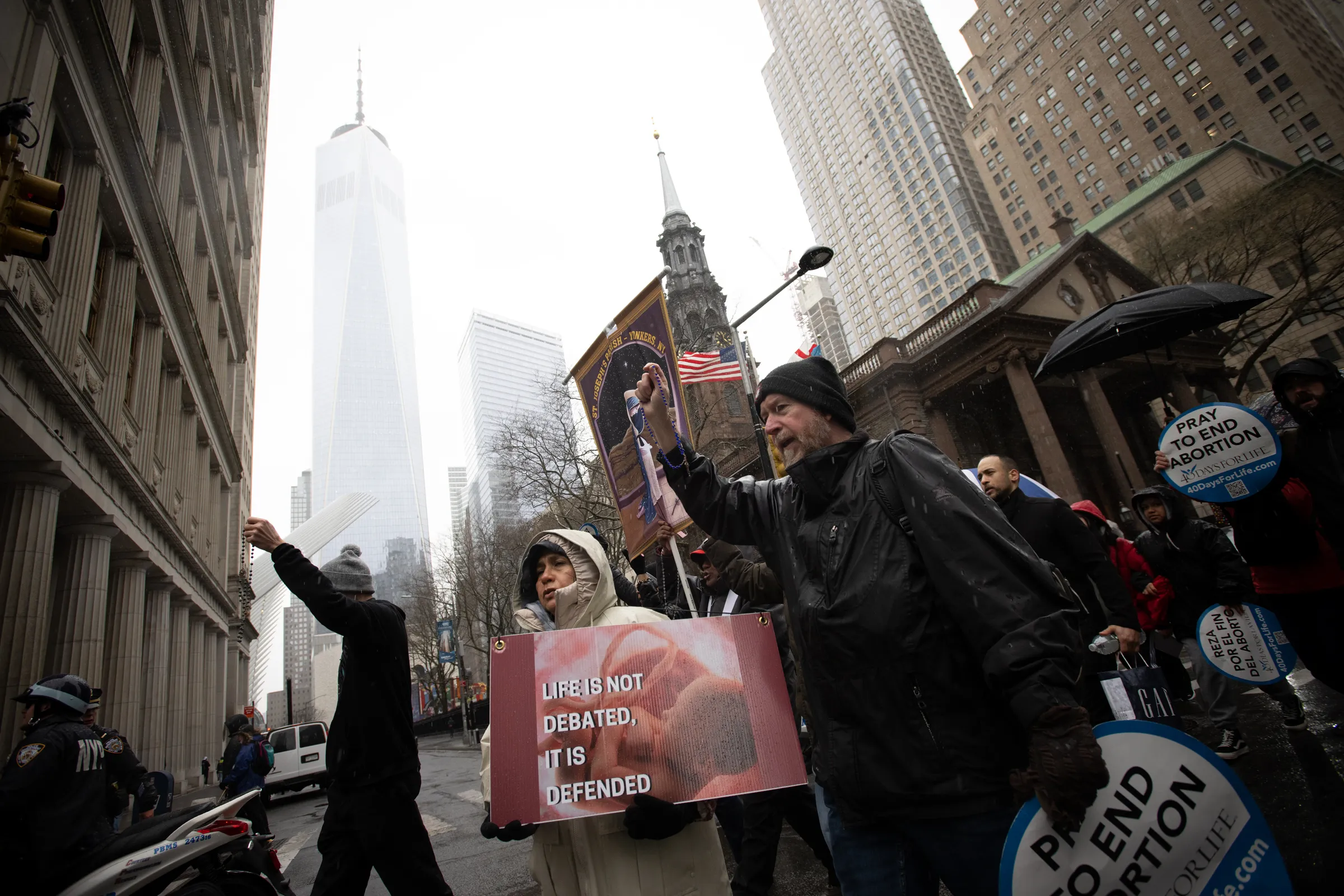 Michael Phelps of Good Counsel Homes prays the rosary with others as they pass Trinity Church in the shadow of the Freedom Tower in Lower Manhattan on March 25, 2023.?w=200&h=150