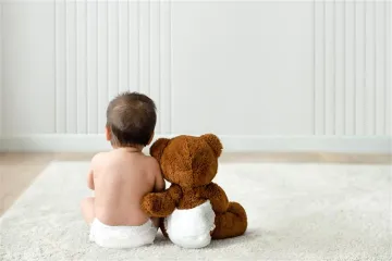 Baby in diapers with teddy bear
