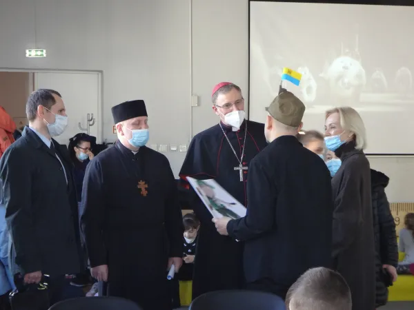 Leonid Grebennyk, Father Roman Sapuzhak, Archbishop Stankevičs, and Gabriella Cabiere speak with a Ukrainian refugee during the visit. Archdiocese of Riga