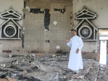 Father Isaac Honsan, pastor of St. Paul's Church, in Imphal, capital of Manipur state, stands in the rubble after the church was set on fire in a recent attack,