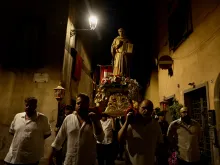 Four men carry a statue of St. Bonaventure during a candlelight procession on July 14, 2023, in Bagnoregio, Italy, his birthplace, on the vigil of the saint's feast day.