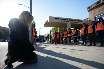 Pro-lifers kneels in prayer in front of abortion clinic