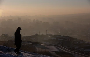 This picture taken on Jan. 16, 2022, shows a man watching smoke hanging over houses on a polluted day in Ulaanbaatar, the capital of Mongolia. Credit: Byambasuren Byamba-Ochir/AFP via Getty Images
