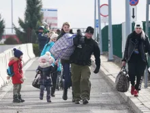 Ukrainian women with children are helped to carry their bags by a Polish border guard as Ukrainian refugees cross the border from Ukraine to Poland at the Korczowa-Krakovets border crossing, Poland, on February 26, 2022, following the Russian invasion of Ukraine.