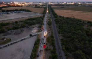In this aerial view, members of law enforcement investigate a tractor trailer on June 27, 2022 in San Antonio, Texas. According to reports, at least 46 people, who are believed migrant workers from Mexico, were found dead in an abandoned tractor trailer. Over a dozen victims were found alive, suffering from heat stroke and taken to local hospitals. Jordan Vonderhaar/Getty Images