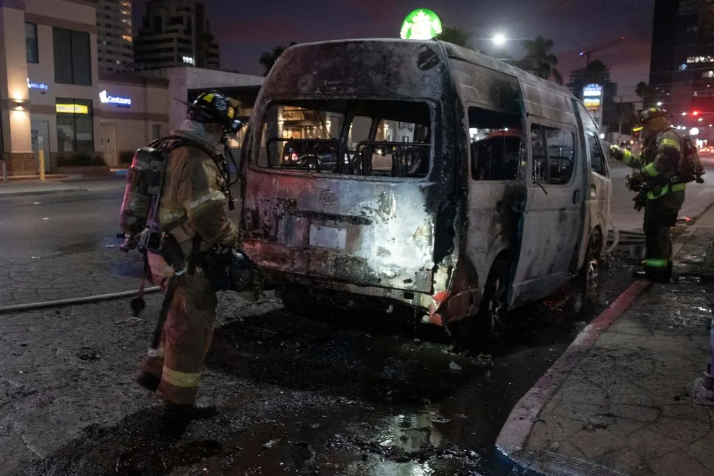 Firefighters work at the scene of a burnt collective transport vehicle after it was set on fire by unidentified individuals in Tijuana, Baja California state, Mexico, on Aug. 12, 2022.?w=200&h=150