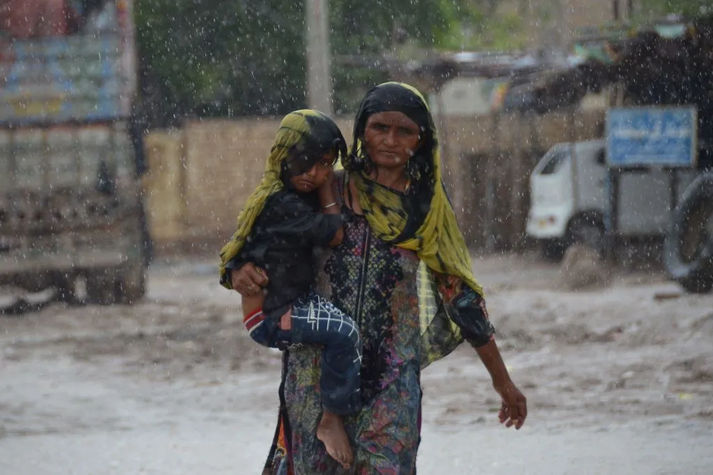 A woman carrying a child walks along a street during a heavy rainfall in the flood-hit Dera Allah Yar town in Jaffarabad district, Balochistan province, Pakistan, on Aug. 30, 2022. Aid efforts ramped up across flooded Pakistan to help tens of millions of people affected by relentless monsoon rains that have submerged a third of the country and claimed more than 1,100 lives.?w=200&h=150