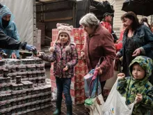 Lybicheva Nina, 72, along with her grandchildren receives food items during a distribution to about 3,000 people by the local branch of Caritas Internationalis, a Catholic charity organization, in Kharkiv, Ukraine, on Sept. 27, 2022.