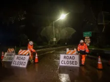 Road workers close the access to the 101 Freeway at Olive Mill Road as a result of San Ysidro Creek overflowing due to heavy rainfall in the area on Jan. 9, 2023, in Montecito, California. The town was ordered evacuated on Monday with firefighters warning mudslides could engulf homes. Montecito, a town of about 9,000 people, was expected to get up to eight inches of rain in 24 hours —on hillsides already sodden by weeks of downpours.