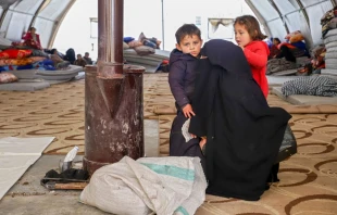 A Syrian woman and her children warm by a stove at an emergency shelter in the center of the city of Maarat Misrin, in the rebel-held northern part of the northwestern Idlib province Feb. 7, 2023, one day after a deadly earthquake hit Syria and Turkey. Photo by ABDULAZIZ KETAZ/AFP via Getty Images