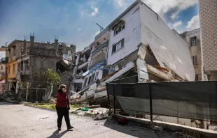 A pedestrian uses a smartphone as she walks past a collapsed building in Antakya, southern Turkey on Feb. 21, 2023. A 6.4-magnitude earthquake late Feb. 20, 2023, rocked Turkey's southern province of Hatay and northern Syria. Photo by SAMEER AL-DOUMY/AFP via Getty Images