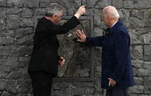 President Joe Biden and Father Richard Gibbons share an umbrella as President Biden touches the original stone from the apparition gable in the rain during a visit to Knock Shrine, on April 14, 2023, on the last day of a four-day trip to Northern Ireland and Ireland. Photo by JIM WATSON/AFP via Getty Images
