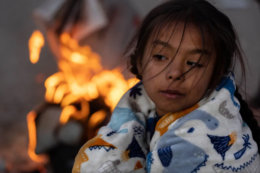 Migrants, including Blaidimar, 8, from Venezuela, warm themselves by a fire outside the U.S.-Mexico border fence while waiting to make asylum claims in El Paso, Texas, on Dec. 21, 2022, as seen from Ciudad Juarez, Mexico.?w=200&h=150