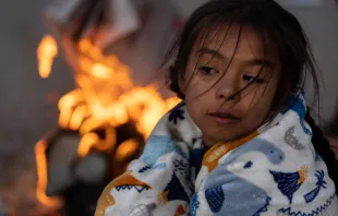 Migrants, including Blaidimar, 8, from Venezuela, warm themselves by a fire outside the U.S.-Mexico border fence while waiting to make asylum claims in El Paso, Texas, on Dec. 21, 2022, as seen from Ciudad Juarez, Mexico. Photo by John Moore/Getty Images