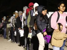 Immigrants seeking asylum in the United States stand in line to be processed by U.S. Border Patrol agents in the early morning hours after crossing into Arizona from Mexico on May 10, 2023, in Yuma, Arizona.