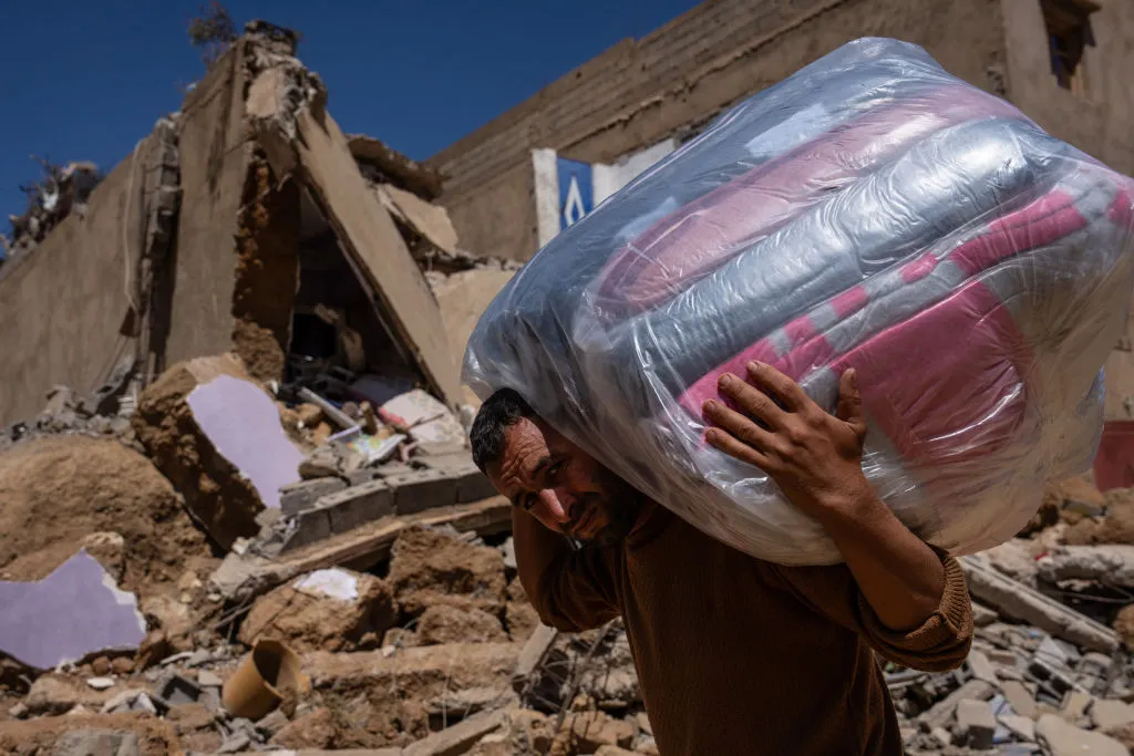 A man carries donated bedding on Sept. 13, 2023, past buildings that were ruined in the Sept. 8 earthquake in Ardouz, Morocco.?w=200&h=150