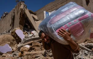 A man carries donated bedding on Sept. 13, 2023, past buildings that were ruined in the Sept. 8 earthquake in Ardouz, Morocco. Credit: Carl Court/Getty Images