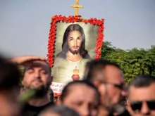 A mourner holds up an image of the Sacred Heart of Jesus at the funeral on Sept. 27, 2023, of victims who were killed when a fire ripped through a crowded wedding hall in the mainly Christian northern city of Qaraqosh, Iraq, also known as Hamdaniyah. At least 100 people were killed, officials said, pointing to indoor fireworks as the likely cause for the blaze that sparked a panicked stampede for the exits.