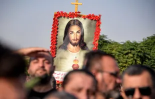 A mourner holds up an image of the Sacred Heart of Jesus at the funeral on Sept. 27, 2023, of victims who were killed when a fire ripped through a crowded wedding hall in the mainly Christian northern city of Qaraqosh, Iraq, also known as Hamdaniyah. At least 100 people were killed, officials said, pointing to indoor fireworks as the likely cause for the blaze that sparked a panicked stampede for the exits. Credit: ZAID AL-OBEIDI/AFP via Getty Images