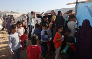 Displaced Palestinians who fled their houses amid Israeli strikes wait at a food distribution point as they shelter in tents set up in a United Nations-run center following Israel's call for more than 1 million civilians in northern Gaza to move south, in Khan Yunis, in the southern Gaza Strip on Oct. 26, 2023, amid the ongoing battles between Israel and the Palestinian group Hamas. Credit: MOHAMMED ABED/AFP via Getty Images