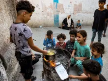 Children sit together around a boy cooking instant noodles on a fire in a makeshift oven from a recycled barrel in Rafah in the southern Gaza Strip on Oct. 31, 2023, amid ongoing battles between Israel and Hamas.