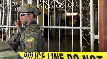 Military personnel stand guard at the entrance of a gymnasium while police investigators look for evidence after a bomb attack at a Catholic Mass at Mindanao State University in Marawi, Lanao del sur province in the southern Philippines on Dec. 3, 2023. At least three people were killed and seven wounded, officials said.