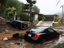 A person attempts to clear away debris from a mudslide as a powerful long-duration atmospheric river storm, the second in less than a week, continues to impact Southern California on Feb. 5, 2024, in Beverly Hills, California.