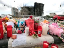 This photograph shows flowers and candles laid out on the sidewalk after a huge fire killed ten people in a multi-story residential block, in Valencia on February 26, 2024. Ten people have died in a vast fire that ripped through a 14-story apartment block in Valencia in eastern Spain.