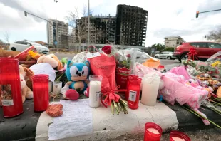 Flowers and candles are laid out on the sidewalk on Feb. 26, 2024, after a huge fire killed 10 people in a multi-story residential block in Valencia, Spain, on Feb. 22. Credit: MAO/AFP via Getty Images