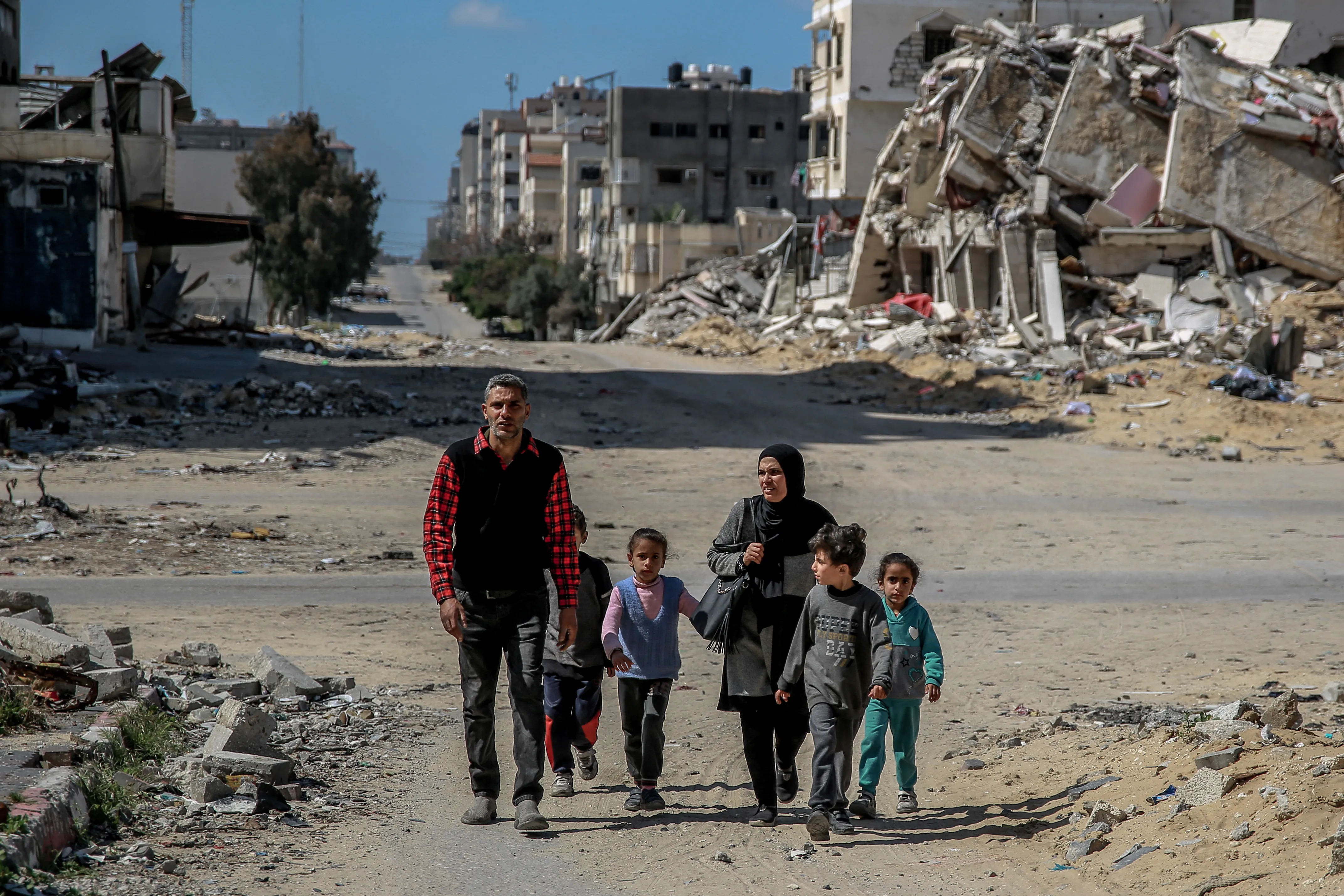 A Palestinian family walks past buildings destroyed in previous Israeli strikes in Gaza City on March 25, 2024, amid the ongoing conflict between Israel and Hamas.?w=200&h=150