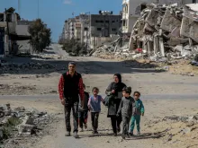 A Palestinian family walks past buildings destroyed in previous Israeli strikes in Gaza City on March 25, 2024, amid the ongoing conflict between Israel and Hamas.