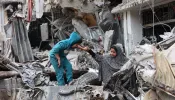 A Palestinian woman assists a child playing on the ruinas of a building destroyed by earlier Israeli bombardment in Gaza City on April 8, 2024, amid the ongoing conflict between Israel and the Palestinian Hamas militant group.