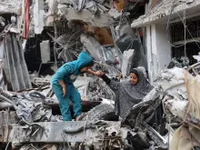 A Palestinian woman assists a child playing on the ruinas of a building destroyed by earlier Israeli bombardment in Gaza City on April 8, 2024, amid the ongoing conflict between Israel and the Palestinian Hamas militant group.
